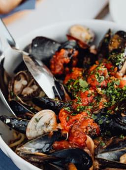 Piatto di cozze e vongole in salsa di pomodoro con prezzemolo.